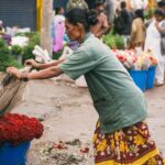 a woman is picking up flowers from a bucket